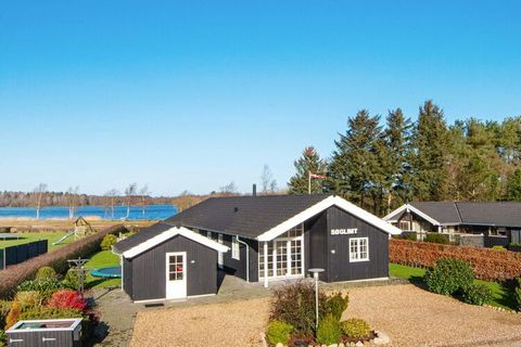 Activity house with panoramic views of Kvie Sø. Open concept kitchen and living room with Scandinavian style furnishings with wood-burning stove and flatscreen-TV. From the living room you have access to the partly covered terrace. One of the bathroo...
